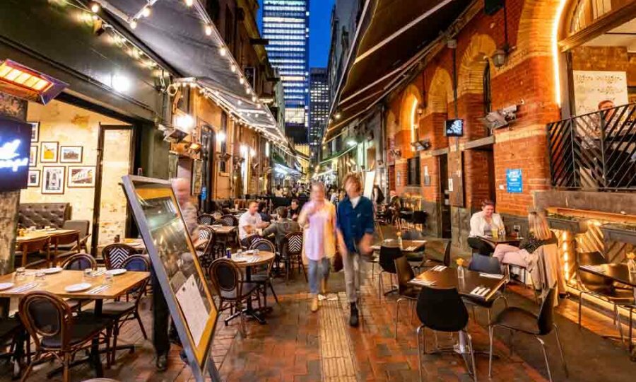 A couple walking down a busy laneway at night