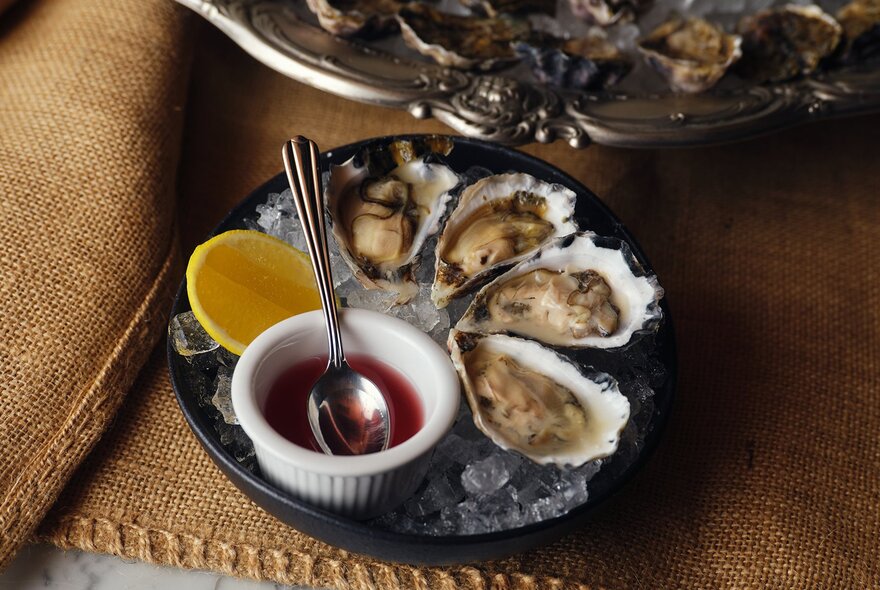 A plate of oysters with a sauce and lemon.