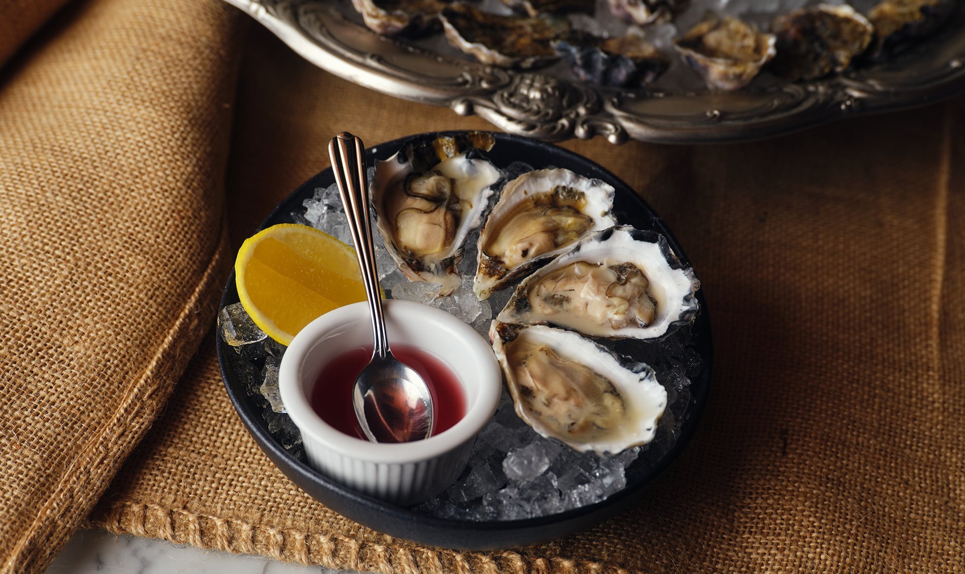 A plate of oysters with a sauce and lemon.