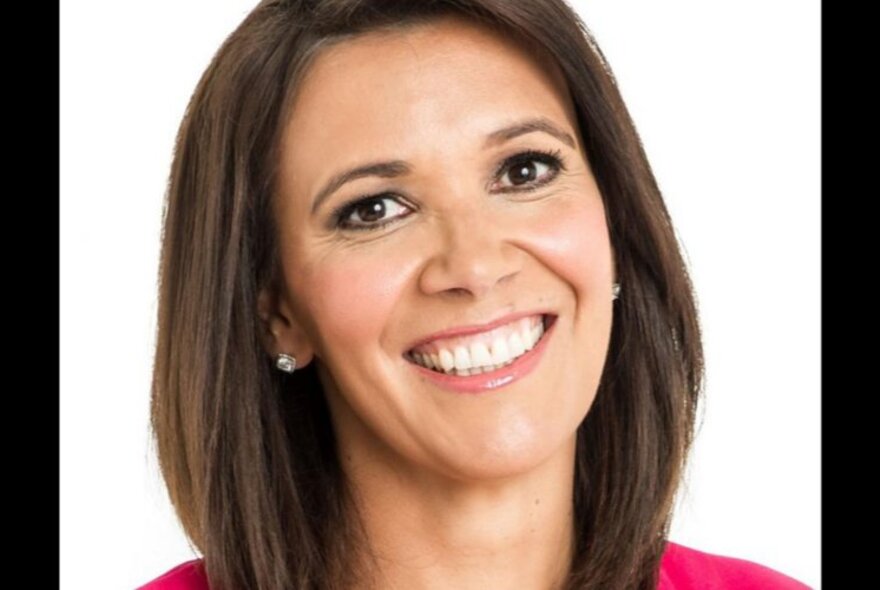 Smiling head shot of Shelley Ware, her teeth showing, and her straight brown hair framing her face, against a white background.