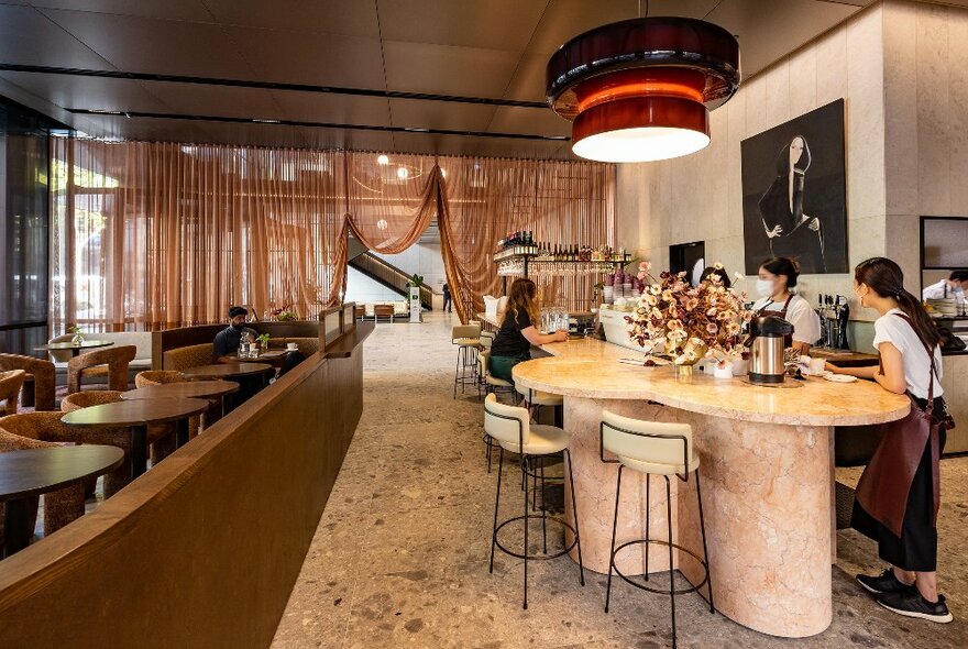 A woman is sitting a restaurant with a large pink marble table 