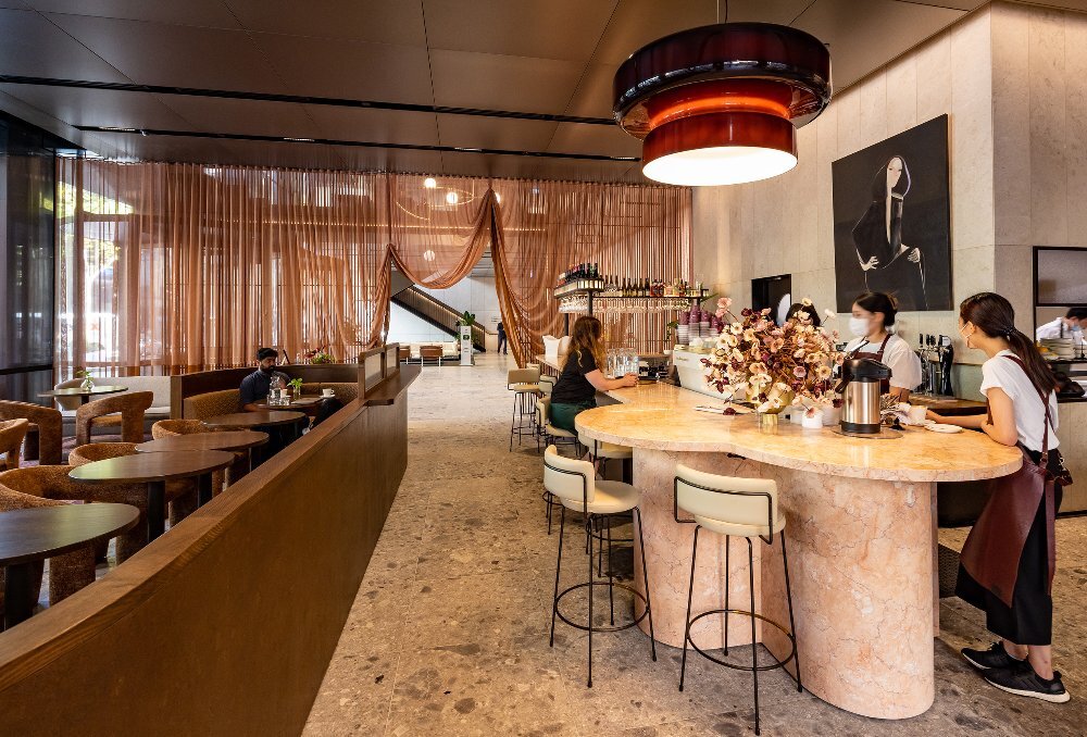 A woman is sitting a restaurant with a large pink marble table 