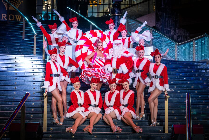 Santa surrounded by his helpers all dressed in red and white outfits, on the grand staircase at Crown Atrium.