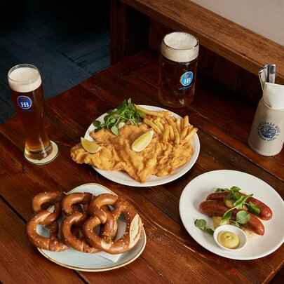 A table with schnitzel, pretzels, sausages and German beer.
