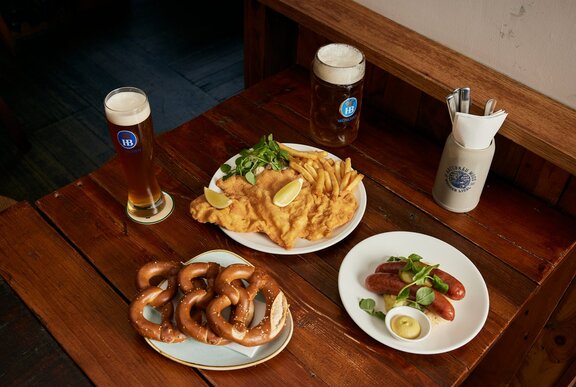 A table with schnitzel, pretzels, sausages and German beer.