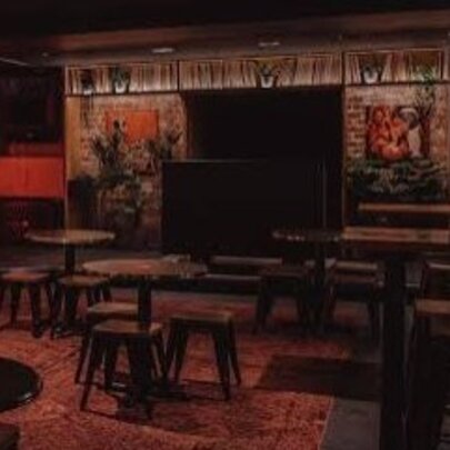 Interior of Wax Music Lounge with empty chairs and tables and a reddish dim glow. 