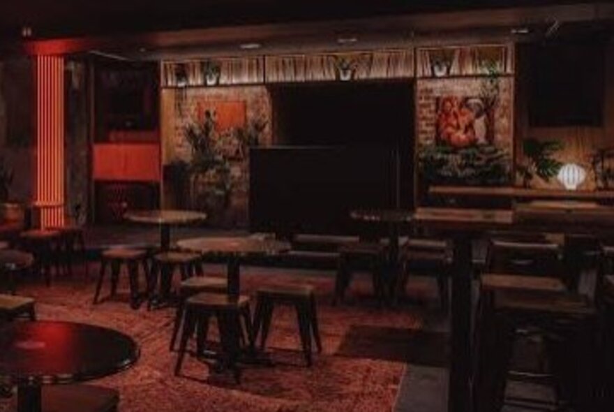 Interior of Wax Music Lounge with empty chairs and tables and a reddish dim glow. 