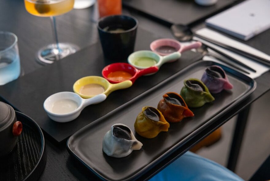 Different coloured dumplings on a black plate