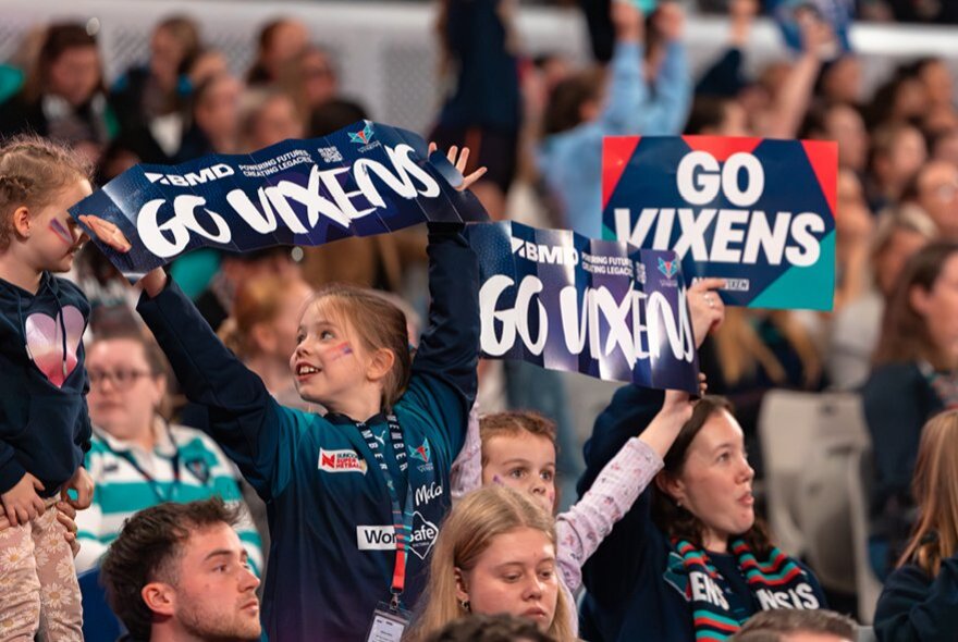 Melbourne Vixens fans in the stands holding Vixens banners.