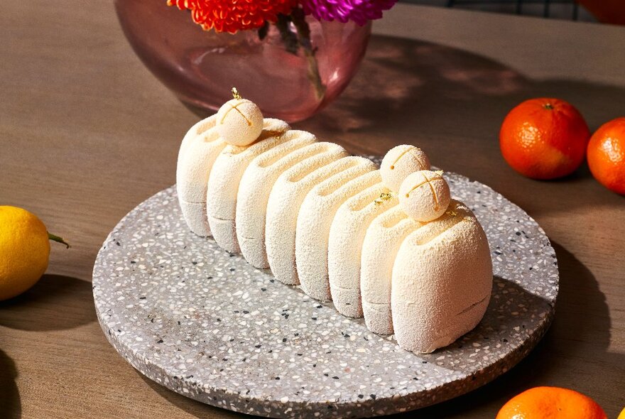 A row of small square shaped white macaroons lined up to make a yule log dessert, on a plate.