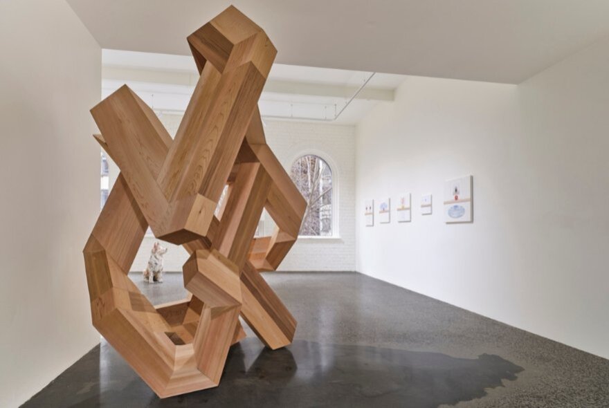 A monumental carved wooden sculpture on display in a gallery setting.