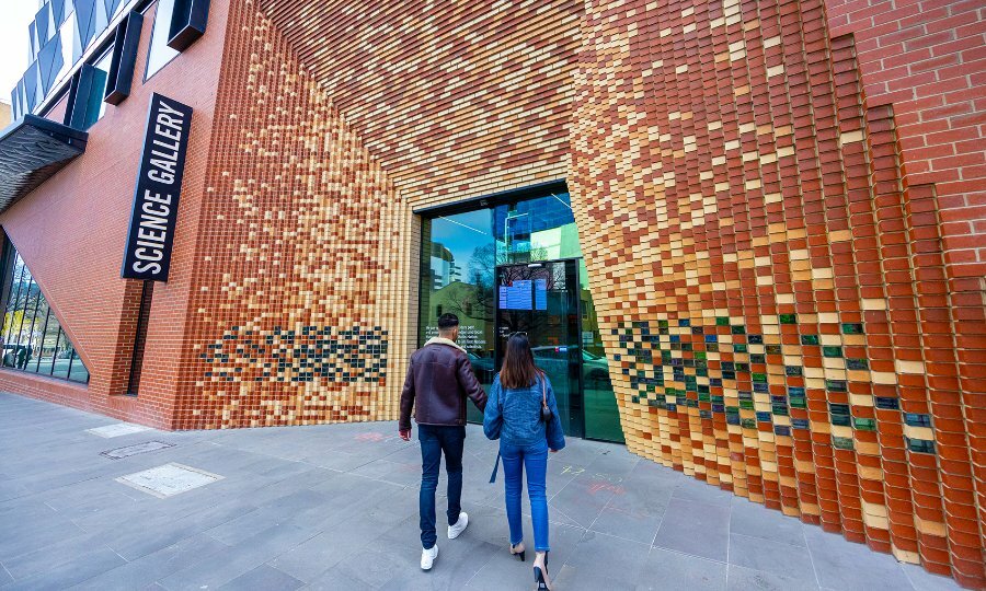 Two people entering a brick gallery.