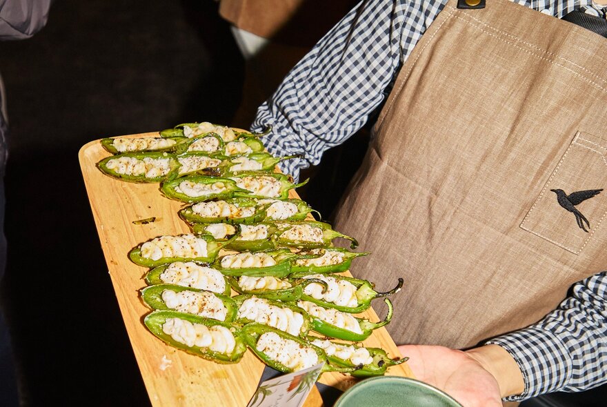 A waiter holding out a wooden tray of canapes.