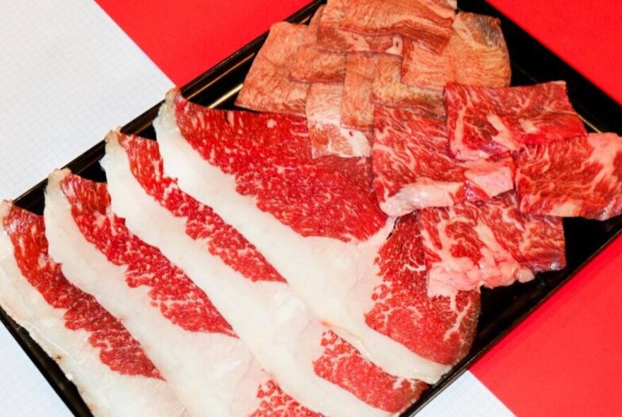 Wagyu beef slices in a black tray.