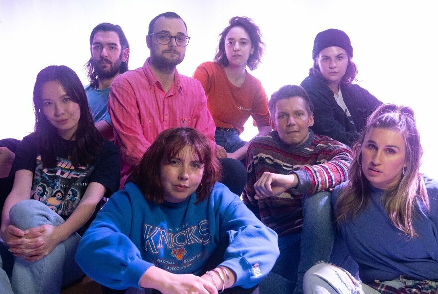 A seated group of improv comedians, all looking seriously at the camera.