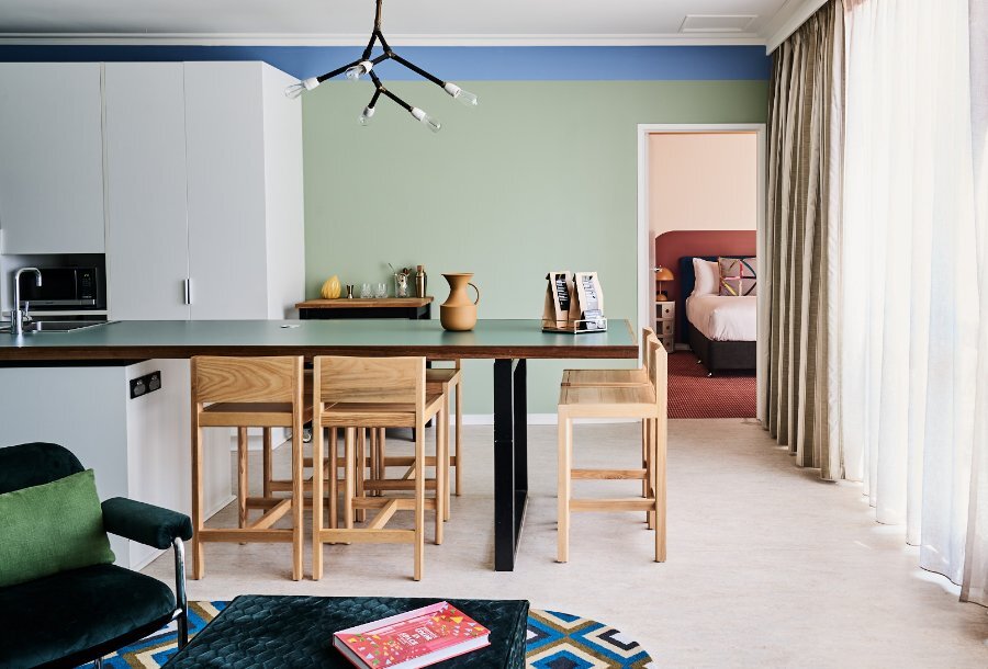 A hotel room with quirky decor, green walls and a light fixture modelled on a tree branch.