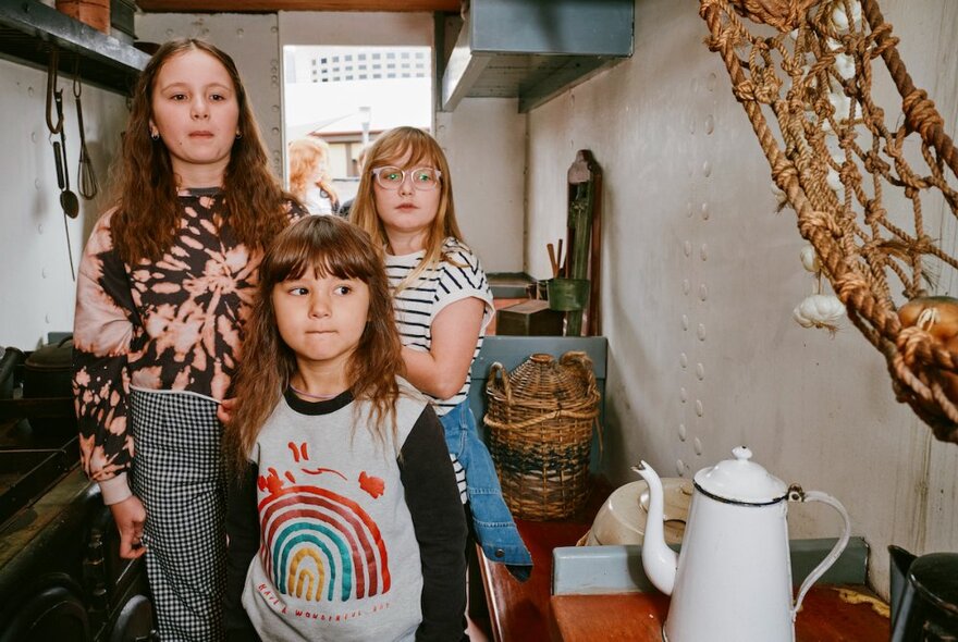 Three girls inside a sailing ship with netted rope and an old enamel teapot.