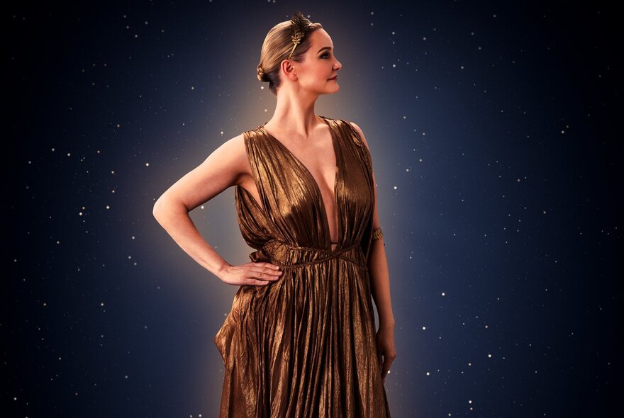 Woman wearing a Grecian gown standing with her hand on her hip.