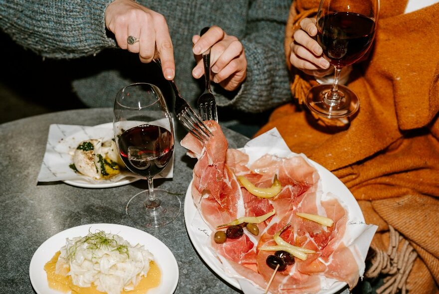 Two people sharing snacks and glasses of wine.