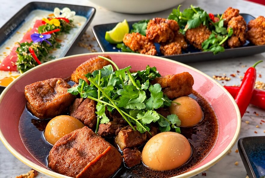 Three Thai-style dishes on a table with chillies.