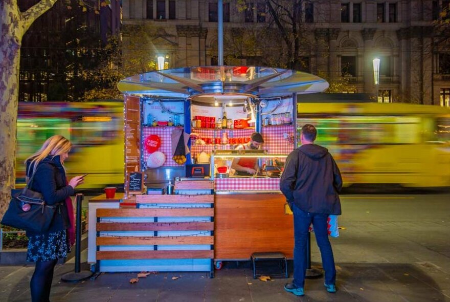 a crepe kiosk with customers standing nearby