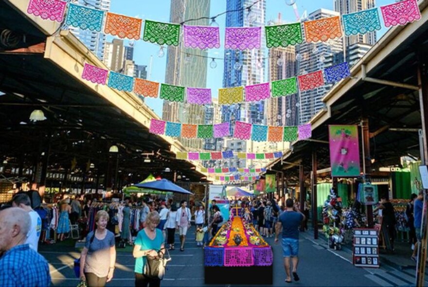 Day of the Dead decorations displayed between the sheds and stalls at Queen Victoria Market, with people walking around underneath.