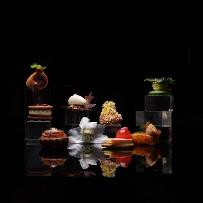Dramatically lit, brightly couloued patisserie against a black background.