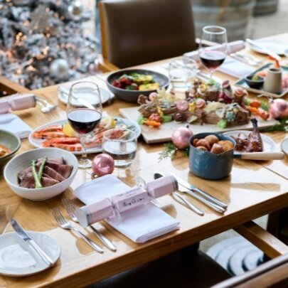 A table in a restaurant filled with plates of festive, seasonal food, and Christmas decorations.
