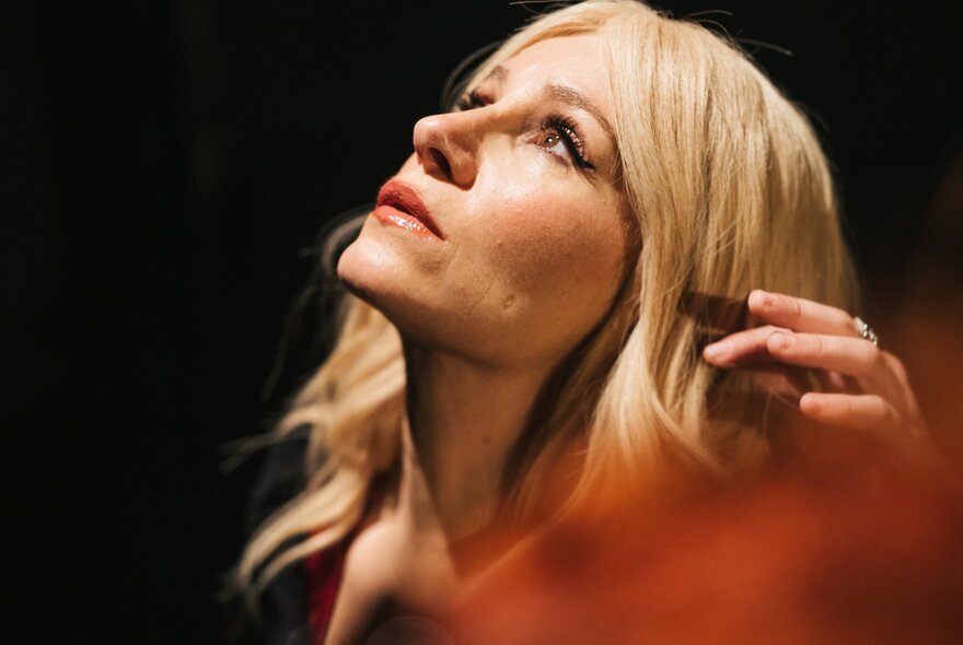 A still from a movie showing an actress in side profile, her head tilted upwards against a dark background. 