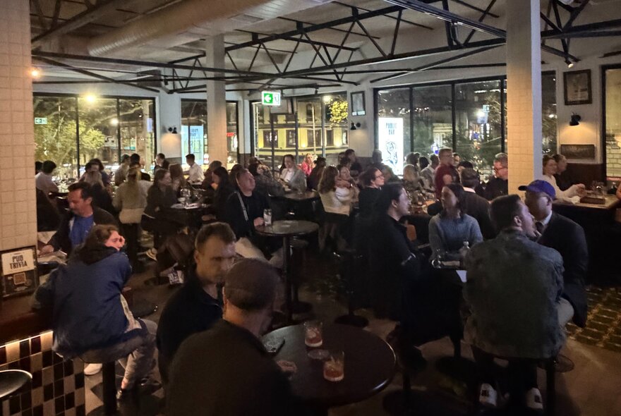 A crowd of people seated at tables inside Springrock Public Bar enjoying drinks and dining, taking part in a trivia quiz.