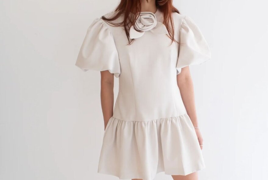 A girl is wearing a cream dress with puffy sleeves