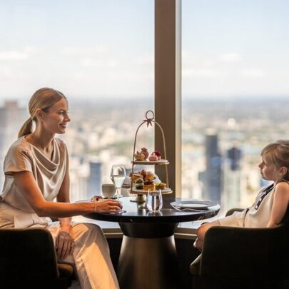 Mother and child seated at a table with afternoon tea display and panoramic views.