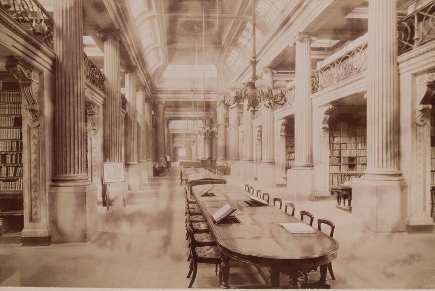 A sepia-toned photograph of the interior of a grand, classical-style library hall with a high ceiling and massive fluted columns lining both sides.