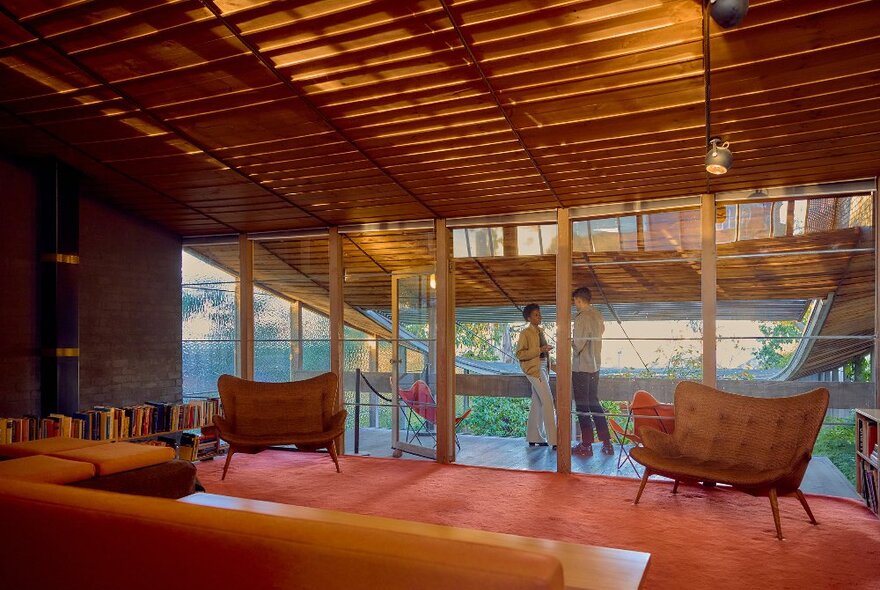 Two friends are sipping on cocktails inside a modernist house