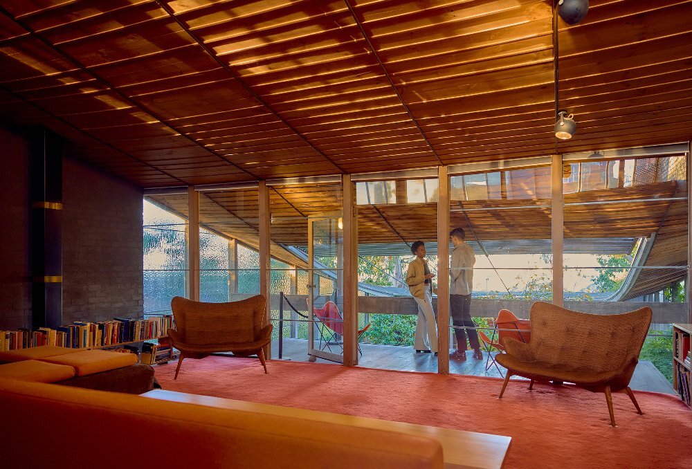 Two friends are sipping on cocktails inside a modernist house
