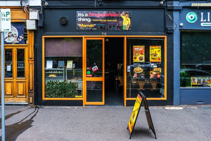 The exterior of a small restaurant painted black and yellow.