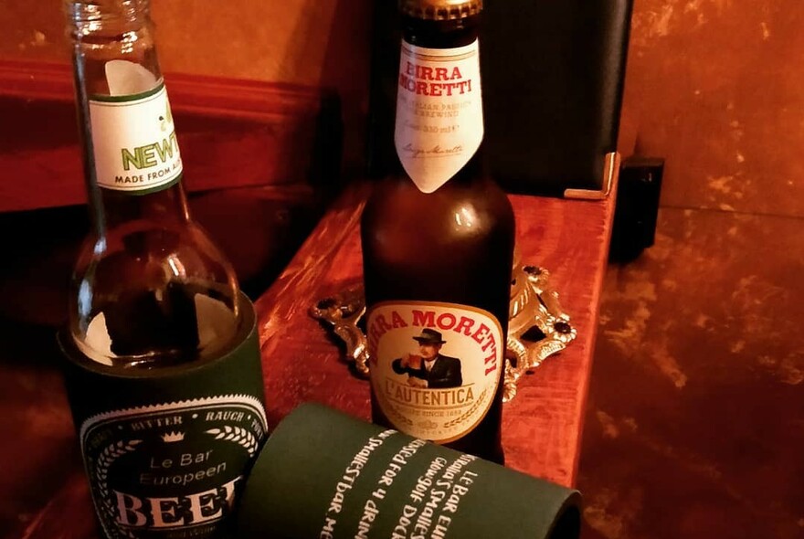 Wooden bar with two beer bottles, a stubby holder and ashtray.