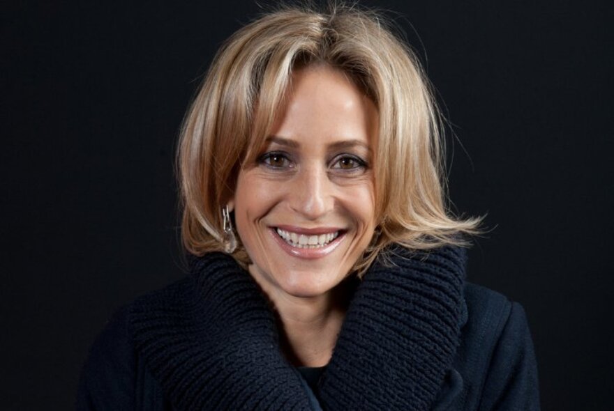 Portrait of acclaimed British journalist, Emily Maitlis, wearing a black, thick-knitted jumper and smiling directly at the camera.