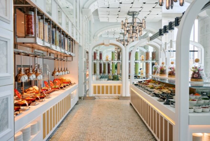 The dinner buffet at a glamourous restaurant with white archways and chandeliers.