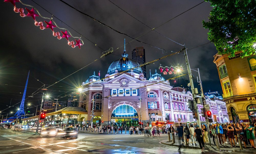 Flinders Street Station glowing blue at night with Christmas decorations.