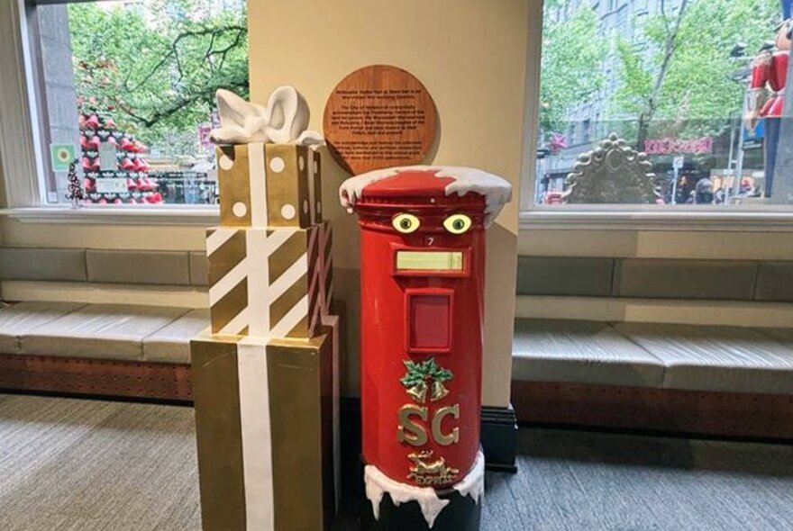 A red mailbox with light up eyes next to a present display.