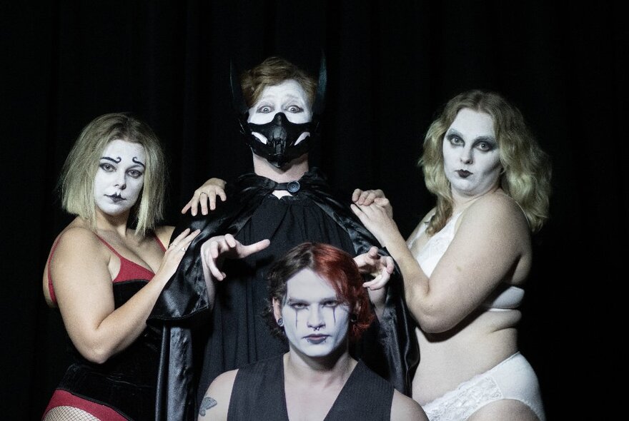 The cast of the cabaret, in costume and makeup, posing for the camera against a dark background.