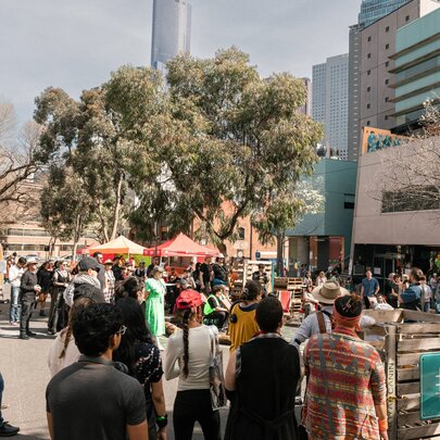 A crowd of people at an outdoor event with market stalls.