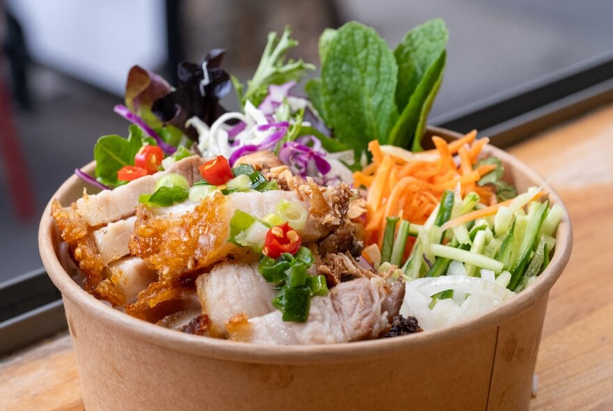 A Vietnamese noodle bowl featuring pork and salad vegetables.