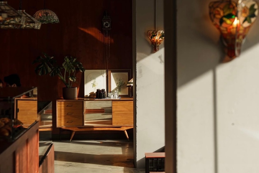Japanese-inspired cafe interior with wooden counter and benches, soft wall light sconces.