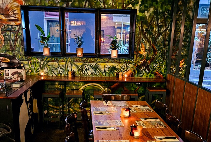 The interior of Matto Napoletano Pizzeria, with green patterned wallpaper and wooden tables and benches.