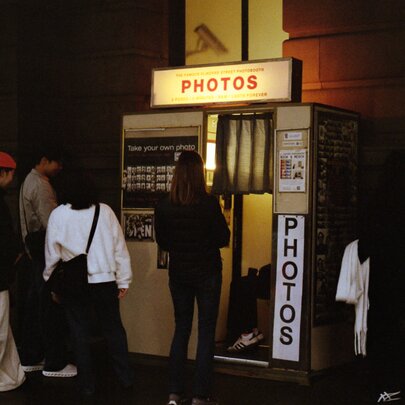 People lining up outside a retro photobooth at night.