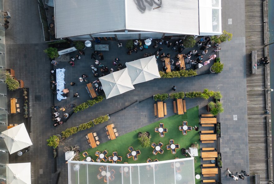 Overhead view of table seating on astroturfed wharf setting with umbrellas.