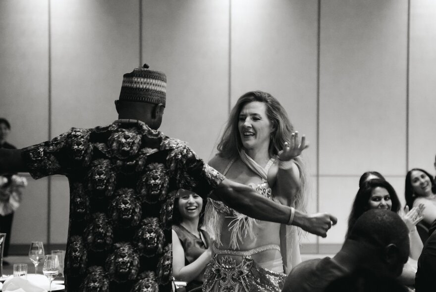 A black and white image of a man and woman in cultural dress, dancing.