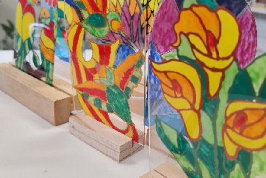Three hand painted glass lamps with wooden bases. 